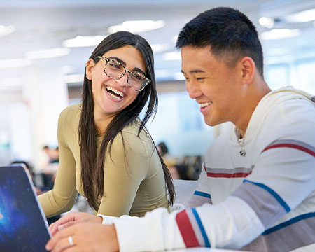 Two international students working together on a laptop