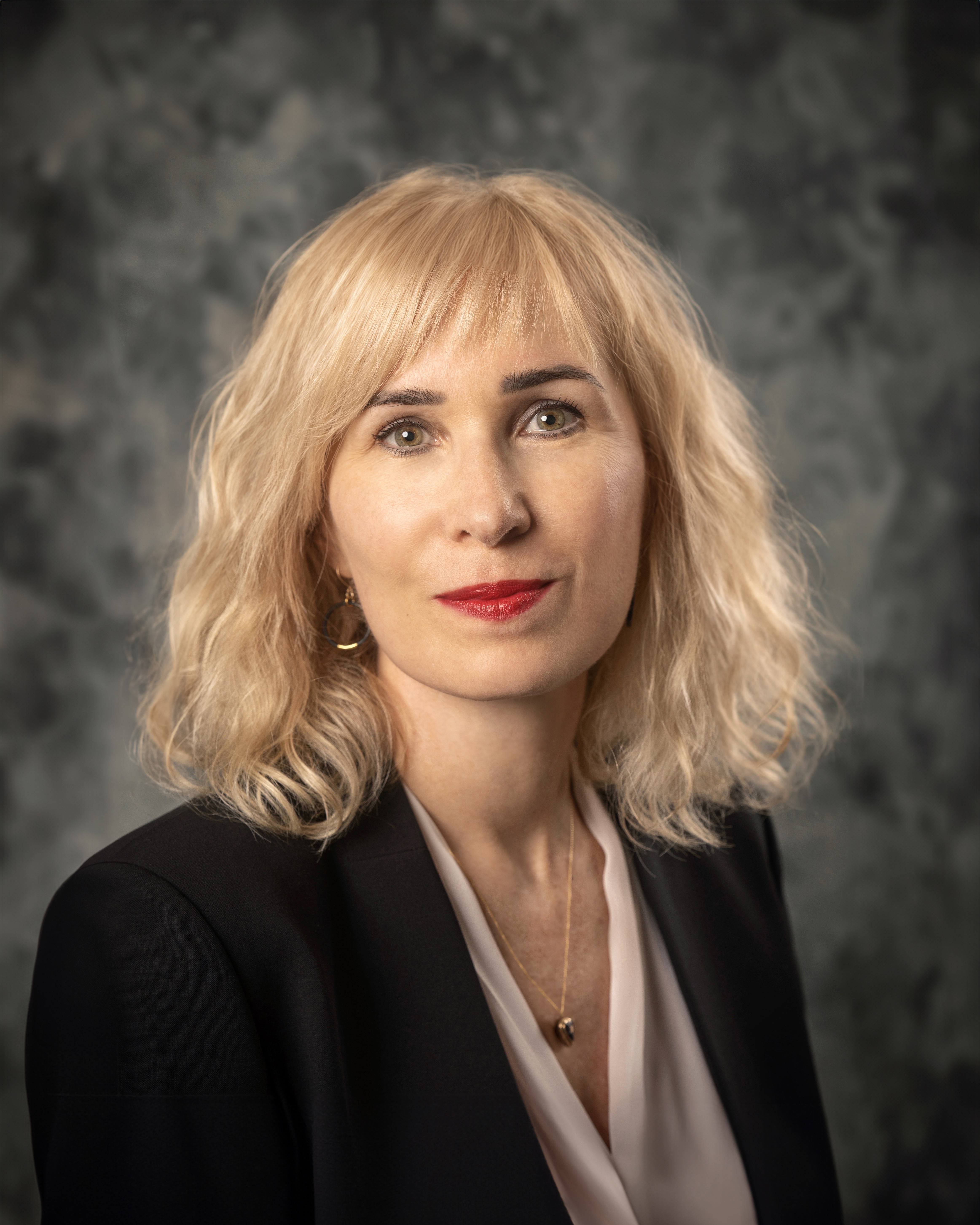 Evelyn Cruise, with shoulder-length blonde hair and red lipstick smiling