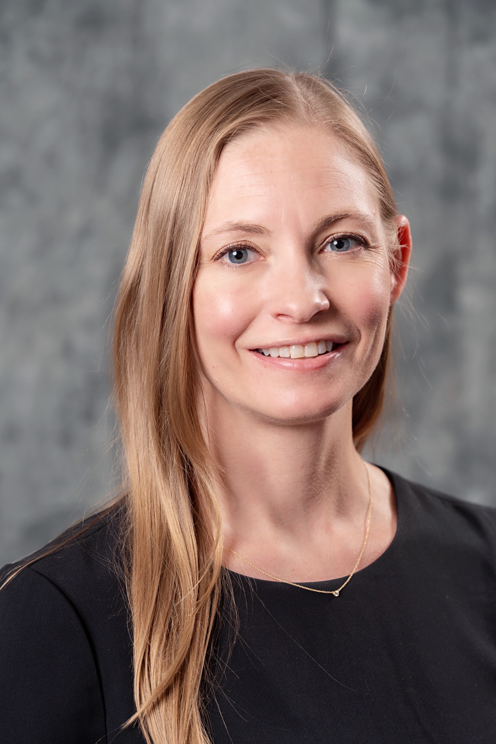 Erica Hackley, wearing a black shirt and necklace smiling at the camera