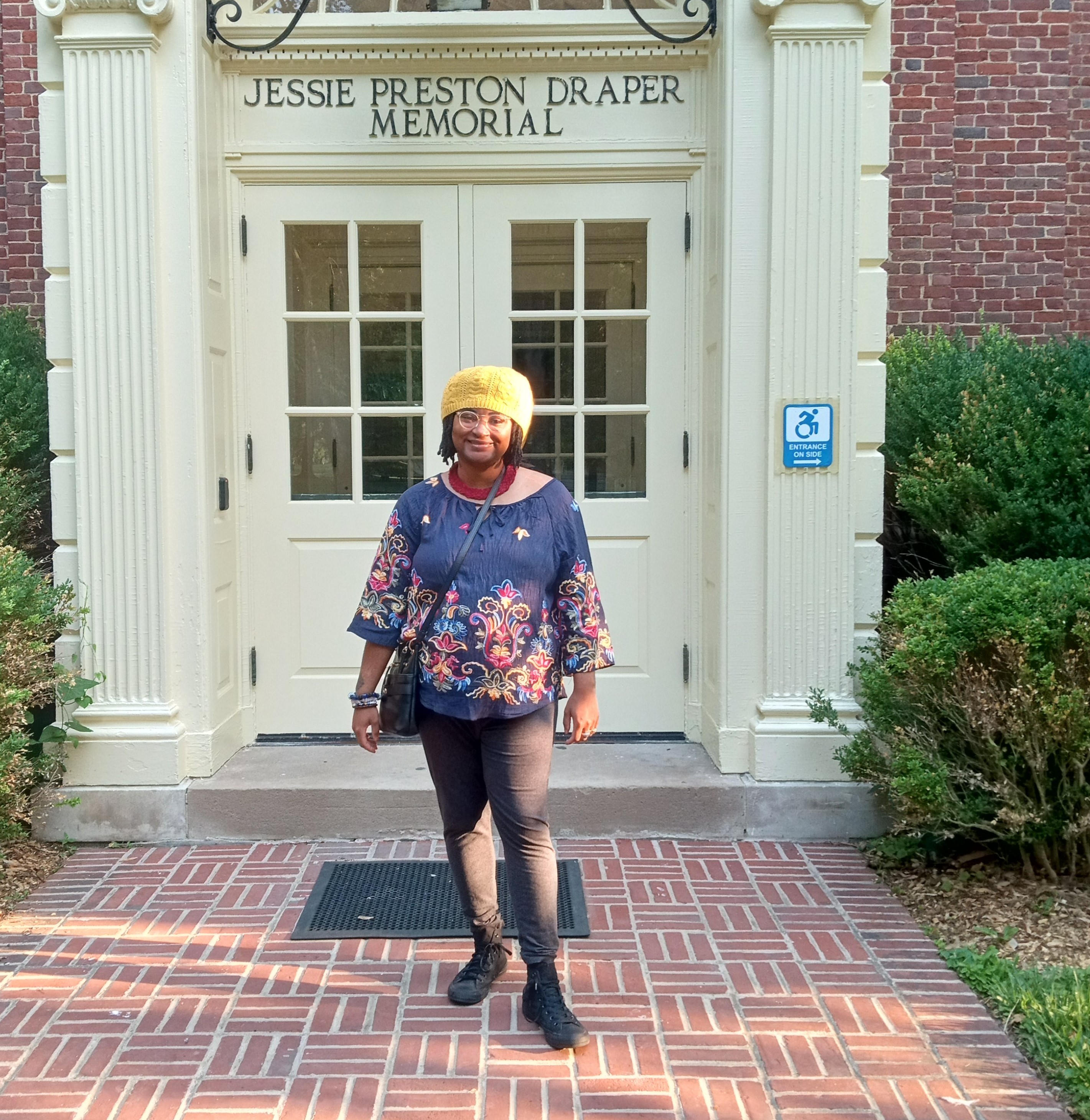 Gabriella Simpson, in a blue top standing in front of white doors