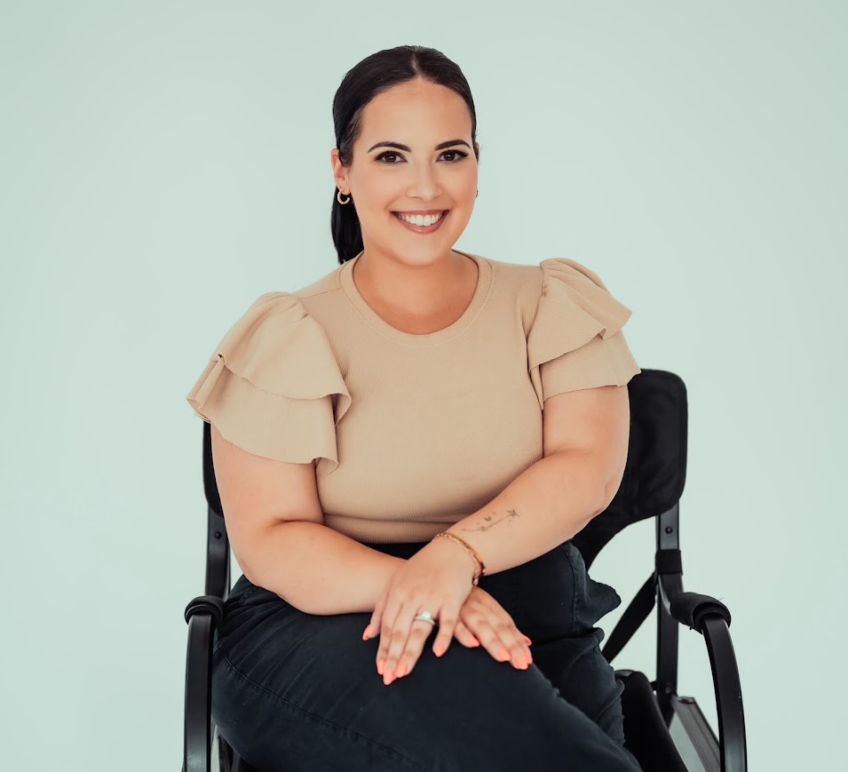 picture of a smiling woman sitting on a black chair in front of a green backround