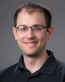 Person in a black shirt and glasses smiling