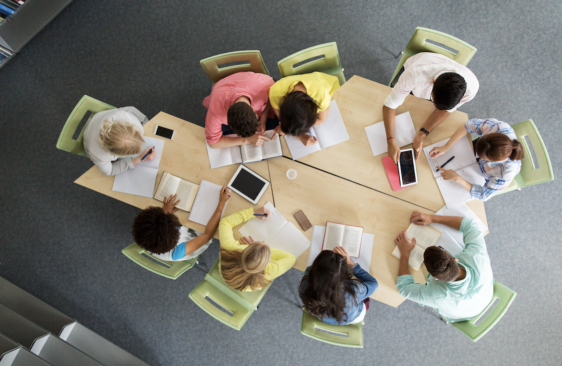 a group of professionals sit around desks working together